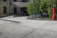 two red post meters with no people at them on a paved sidewalk outside a brick building