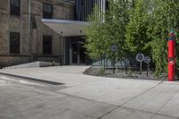 two red post meters with no people at them on a paved sidewalk outside a brick building