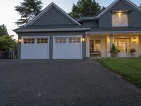 a large two story blue house with a porch and garage on a dark driveway outside