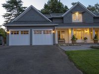 a large two story blue house with a porch and garage on a dark driveway outside