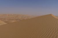 a person riding on top of a sand dune in the desert looking down at its surface