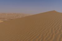 a person riding on top of a sand dune in the desert looking down at its surface