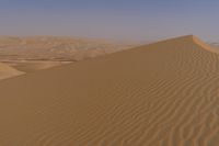 a person riding on top of a sand dune in the desert looking down at its surface