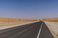 an empty highway in the middle of desert with power poles along the roadsides and poles at each end