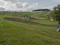 dirt bikers at the top of a steep hill overlooking farm land and green pastures