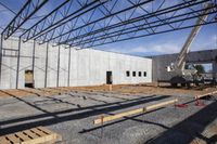 a large building under construction with construction workers working on it and the roof partially covered with metal mesh