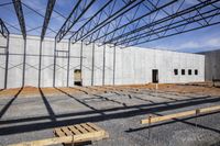 a large building under construction with construction workers working on it and the roof partially covered with metal mesh