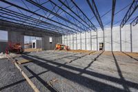 a large building under construction with construction workers working on it and the roof partially covered with metal mesh