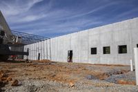 a large building under construction with construction workers working on it and the roof partially covered with metal mesh