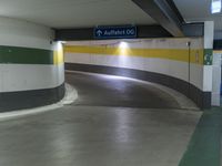 a empty underground parking garage with signs showing location and direction, located inside of building