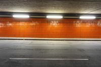 a long empty parking space with yellow walls and orange tile walls and white lines down the length