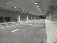 a street with white lines in an underground parking garage area at night, with a red traffic light on and overhead lighting in the ceiling