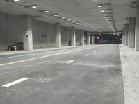 a street with white lines in an underground parking garage area at night, with a red traffic light on and overhead lighting in the ceiling