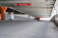 an underground parking garage with concrete floors, cement walls and multiple orange painted do not enter signs