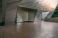 an elevator leading into an underground, modern building with silver metal facade and decorative patterning on the walls