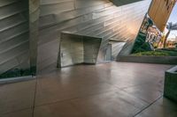 an elevator leading into an underground, modern building with silver metal facade and decorative patterning on the walls