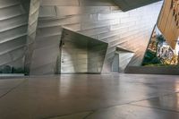 an elevator leading into an underground, modern building with silver metal facade and decorative patterning on the walls