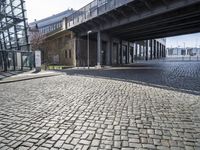 a view of the brick road from a bus stop under a bridge that overlooks a plaza in front