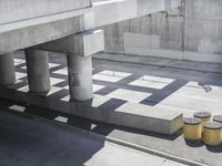 a parking space that is under a large concrete building with a fire hydrant on the sidewalk