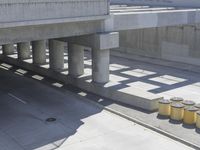 a parking space that is under a large concrete building with a fire hydrant on the sidewalk