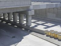 a parking space that is under a large concrete building with a fire hydrant on the sidewalk