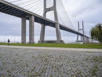 the view from under a bridge of a road and a grass field in front of it