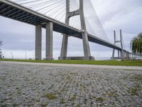 the view from under a bridge of a road and a grass field in front of it