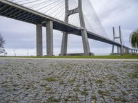 the view from under a bridge of a road and a grass field in front of it