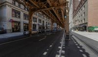 the view down the street from underneath the train tracks on a city street lined with buildings and cars