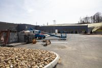 an unfinished building with construction equipment next to a pile of rocks and a crane at work