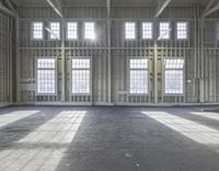 the inside of a unfinished factory with floor to ceiling windows and light streaming through windows