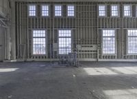 the inside of a unfinished factory with floor to ceiling windows and light streaming through windows