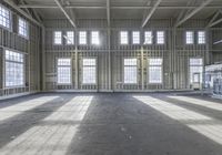 the inside of a unfinished factory with floor to ceiling windows and light streaming through windows