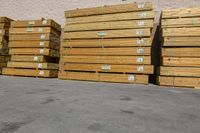 pallets in an unfinished warehouse sitting outside a building on a sidewalk next to a stack of yellow crates