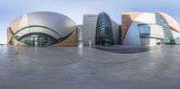 multiple spherical pictures show an unusual modern building and sky in a city setting with blue sky