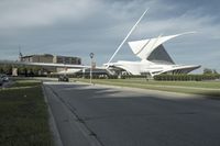 an unusual building in a big city, near the road corner with cars parked nearby