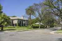 street corner at an upscale residential area with palm trees in foreground and apartment complex to the right