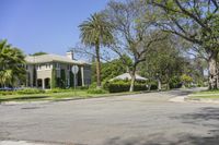 street corner at an upscale residential area with palm trees in foreground and apartment complex to the right