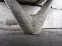 an upside down concrete structure sits on the cement floor with a white wall behind it