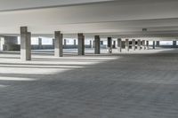 a long hallway with a railing and a line of parked cars in it, inside an airport