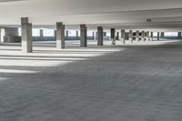 a long hallway with a railing and a line of parked cars in it, inside an airport