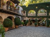 an alley with arches and potted plants on either side of it to make it easier to find a room