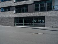 an empty street with a large building in the background, glass windows and stone facade