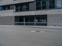 an empty street with a large building in the background, glass windows and stone facade