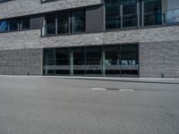 an empty street with a large building in the background, glass windows and stone facade