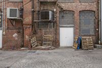 old red brick building with doors on one side and boxes outside, along with debris