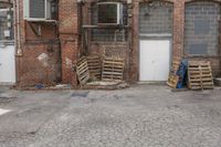 several crates and one blue bag in front of a building with windows and some closed doors