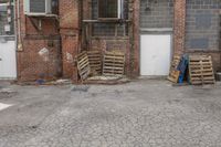 several crates and one blue bag in front of a building with windows and some closed doors