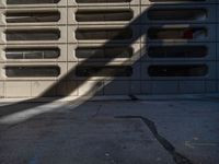 a black fire hydrant stands next to an apartment building that has large windows in the wall