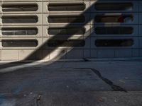 a black fire hydrant stands next to an apartment building that has large windows in the wall